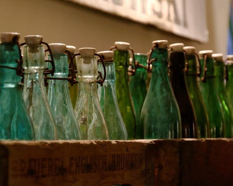 A wooden crate filled with empty green glass bottles ready for filling