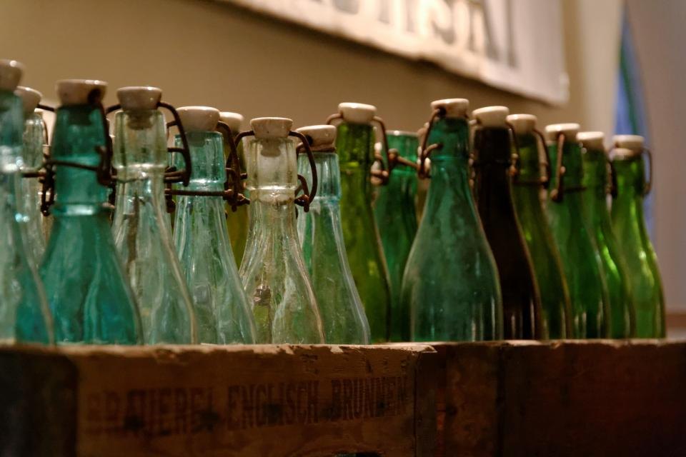 A wooden crate filled with empty green glass bottles ready for filling