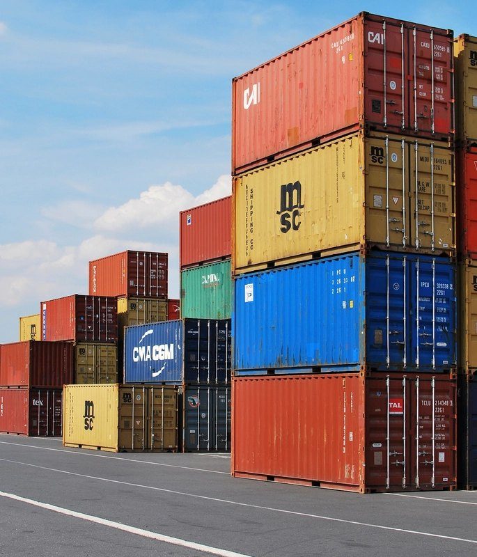 Colourful shipping containers stacked high beside a road at a freight terminal