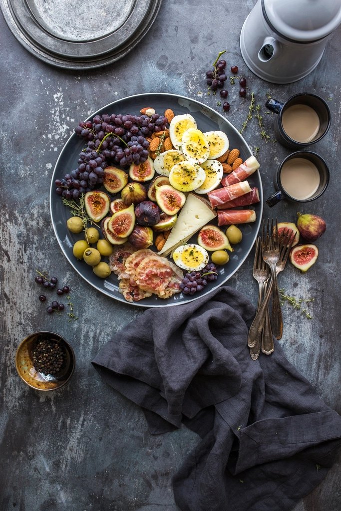 A large sharing platter of olives, figs, cheese and cured meats on a dark table