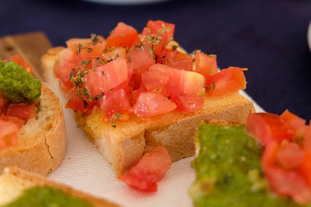 Bruschetta topped with chopped tomato, basil and a drizzle of olive oil on a board