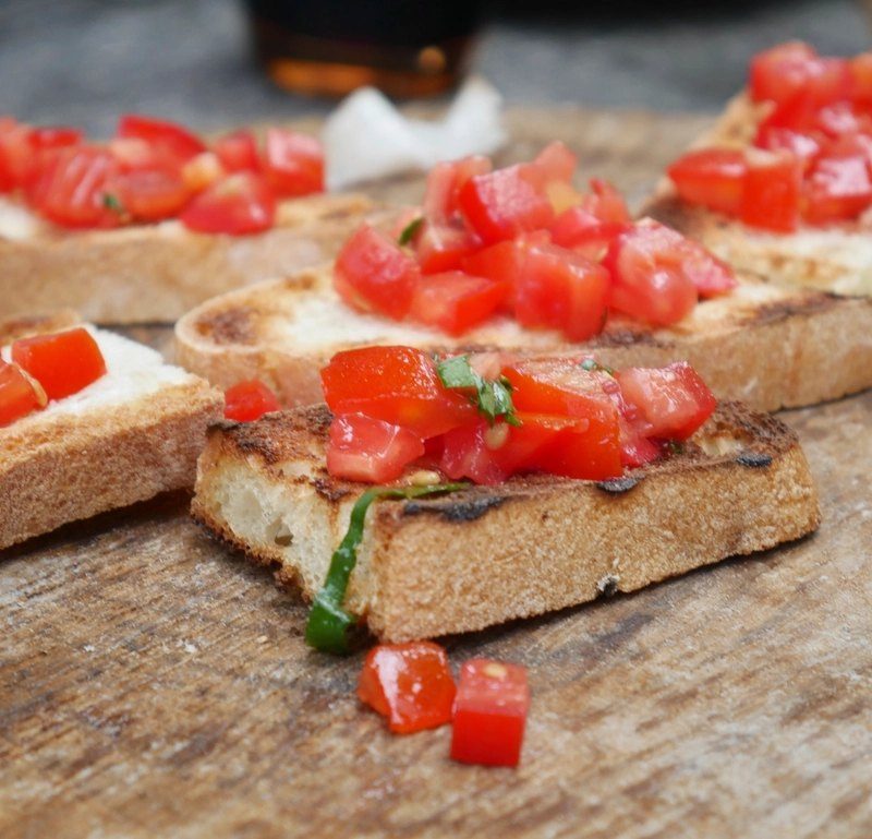 Slices of toasted bread topped with diced tomato and olive oil
